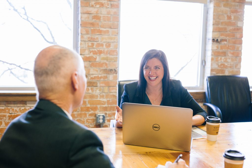 Dois empresários, um homem e uma mulher, sentados em um escritório conversando sobre o que faz um escritório de contabilidade online.